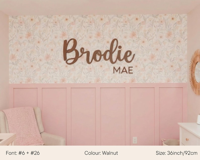 May include: A walnut-colored wooden sign with the name "Brodie" and the name "MAE" below it. The sign is 36 inches (92cm) wide and is displayed on a pink wall with floral wallpaper.