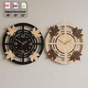 Peut inclure: Deux horloges murales circulaires avec un cadre géométrique et quatre feuilles d'érable. L'une est noire avec des feuilles en bois clair, l'autre en bois clair avec des feuilles marron foncé. Aiguilles dorées, chiffres 3, 6, 9, 12. Téléchargement numérique 18", 15", 12".