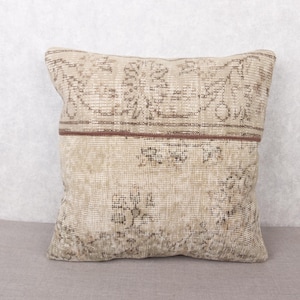 Può includere: Cuscino quadrato beige con un motivo vintage invecchiato nei toni del marrone e beige. Presenta una fascia centrale marrone scuro e un motivo floreale sbiadito, adatto all'arredamento della casa. Misura circa 40 cm x 40 cm.