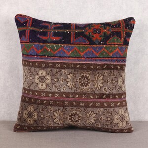 May include: Square decorative pillow with a patchwork design. The top section features a dark blue background with red and green geometric patterns. The middle section has a floral pattern in shades of gray and brown. The pillow is approximately 18 inches square.