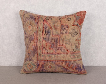 May include: Square cushion with a vintage rug design. The cushion has a beige background with a repeating pattern in shades of red, purple, and blue. The cushion is made of a woven fabric.