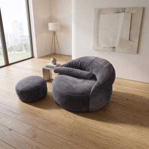 May include: A dark gray corduroy lounge chair with a rounded, low-profile silhouette and a matching cylindrical bolster pillow, accompanied by a small, circular, matching dark gray corduroy ottoman, both featuring a soft, textured fabric finish.