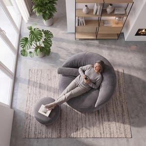 May include: A large, round, grey corduroy lounge chair with a matching cylindrical bolster pillow and a circular ottoman. The chair features a textured fabric surface and a deep, curved seat design, providing a comfortable space for relaxation.