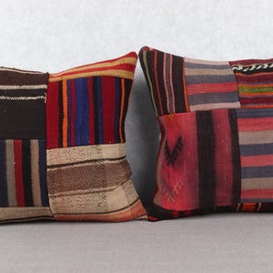 Op de afbeelding: Twee vierkante kussens met een patchwork ontwerp. De kussens hebben een verscheidenheid aan kleuren, waaronder rood, bruin, blauw en beige. Het patchwork ontwerp bevat strepen en geometrische patronen.