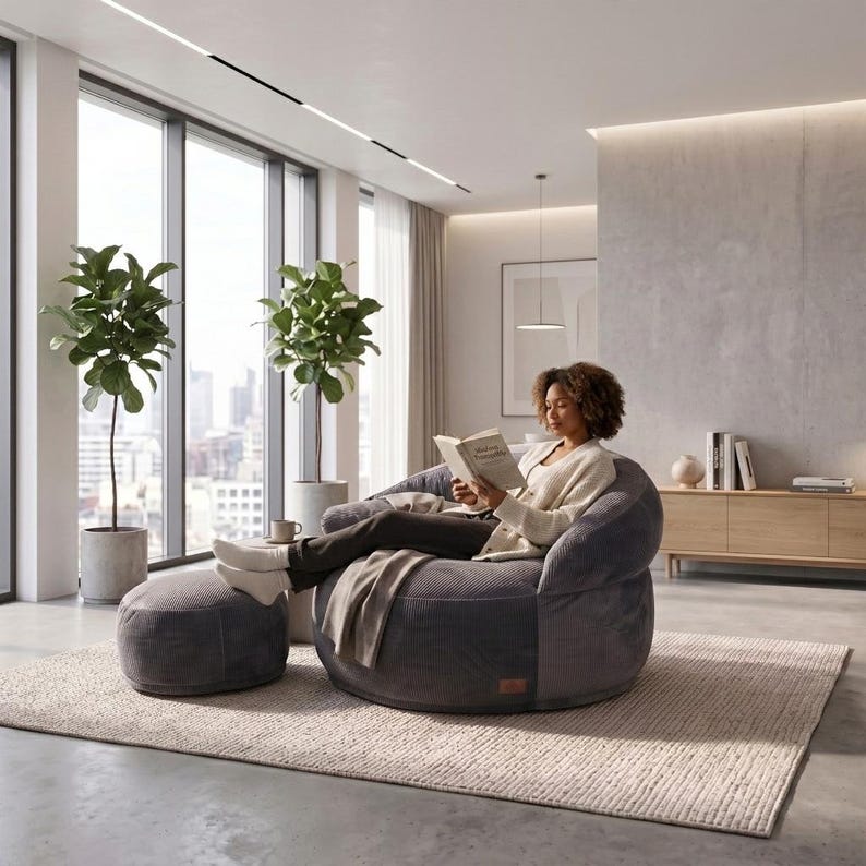 May include: A dark gray corduroy round armchair with a matching circular ottoman. The chair features a deep, cushioned seat and a curved backrest, providing a structured yet soft seating option for a living space, paired with a footrest.