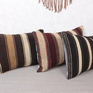Puede incluir: Tres almohadas de tiro a rayas en varios colores y patrones. Las almohadas están hechas de un tejido tejido y tienen una textura suave y cómoda.