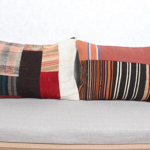 May include: Two rectangular cushions with patchwork designs. One cushion features a mix of colours including red, brown, and white. The other has a striped pattern in orange, black, and white, with a solid terracotta top.
