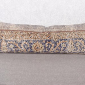 May include: Rectangular decorative pillow with a vintage rug design. The pillow features a central band of blue and gold floral patterns, bordered by a brown and beige design. The pillow's ends are a solid beige color.