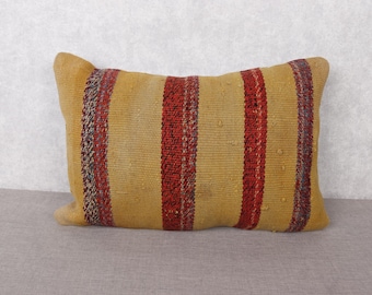 May include: Rectangular decorative pillow with a yellow background and vertical red stripes. The pillow has a textured surface and is designed for home decor. The pillow's dimensions are approximately 12 inches by 20 inches.