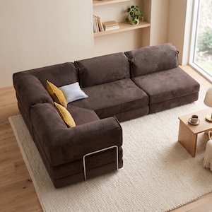 May include: A dark brown corduroy sectional sofa with a low-profile design and a metal frame accent. The sofa features thick, textured cushions and includes two small mustard yellow throw pillows and one light gray throw pillow for contrast.