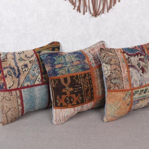 以下が含まれることがあります： パッチワークデザインの正方形のクッション3つ。ベージュ、ブルー、オレンジ、レッドなど、さまざまな色が使われています。パッチワークのデザインは、クッションにヴィンテージまたはボヘミアンな美しさを与えています。