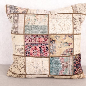 May include: Square patchwork pillow with a variety of colors and patterns. The pillow features a mix of beige, red, blue, and brown patches, creating a vintage aesthetic. The pillow is a decorative item for a sofa or bed.