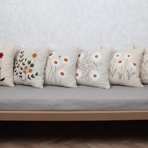 Blommigt broderade örngott – tusensköna, vallmo och botaniska kuddfodral på beige bomull | Rustik modern naturinspirerad inredning