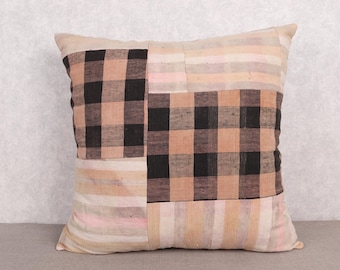 Op de afbeelding: Vierkant decoratief kussen met een patchwork ontwerp. Het kussen heeft een mix van ruit- en streepmotieven in beige, zwart en roze. Het kussen is gemaakt van een zachte, getextureerde stof.