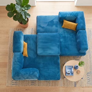 May include: A modular sectional sofa upholstered in blue corduroy fabric, featuring a square ottoman and two rectangular mustard yellow throw pillows. The sofa is arranged in an L-shape configuration, providing a textured surface and deep seating.