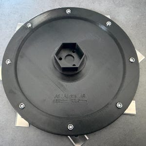 Puede incluir: Una taza de cerámica blanca con un asa negra y el texto "But First, Coffee" en negrita negra. La taza se encuentra sobre un fondo borroso, sugiriendo un ambiente acogedor.