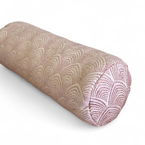 May include: A cylindrical bolster pillow in a soft pink hue, featuring a repeating fan-like pattern in a lighter shade. The pillow's fabric has a subtle sheen, adding to its decorative appeal. This accent pillow is designed for comfort and style.