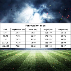 Op de afbeelding: Een maattabel met de titel "Fan version men" met afmetingen in centimeters. De tabel bevat maten S tot XXL, met bijbehorende afmetingen voor lengte, breedte, hoogte en gewicht. De achtergrond is een wazige afbeelding van een voetbalveld.