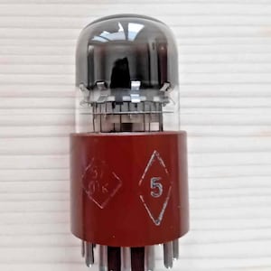 May include: A vintage vacuum tube with a clear glass top and a reddish-brown base. The base has a diamond-shaped design with the number "5" and other markings. The tube has multiple pins at the bottom and is designed for electronic devices.