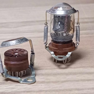 May include: Two vintage vacuum tubes with metal and brown plastic bases. The tubes have a clear glass casing and metal springs.