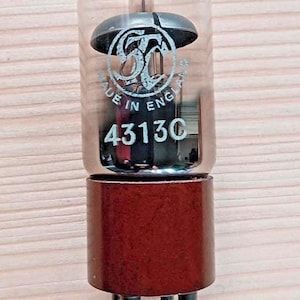 Puede incluir: Válvula de vacío vintage con una bombilla de vidrio transparente, una base marrón oscuro y clavijas plateadas. El tubo tiene el texto "MADE IN ENGLAND" y el número "43130". También es visible el logotipo de GE.