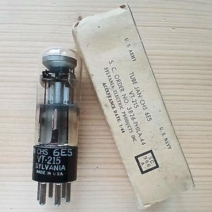 Puede incluir: Tubo de vacío Sylvania VT-215 vintage con su caja original. El tubo tiene una base negra con el texto "CHS 6E5 VT-215 SYLVANIA MADE IN U.S.A.". La caja está etiquetada como "U.S. ARMY" y "U.S. NAVY".