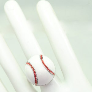 May include: A baseball-themed ring featuring a white ball with red stitching and a silver-colored band. The ring is a sporty accessory, perfect for baseball fans.