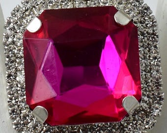 May include: A large, square, pink rhinestone ring with a silver setting and a border of smaller rhinestones.