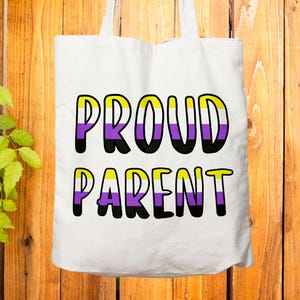 May include: White tote bag featuring the text "PROUD PARENT" in a bold, blocky font. The letters are black-outlined with yellow, purple, and white colour-blocked sections. The bag has two white handles.