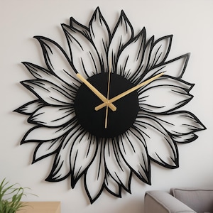 Puede incluir: Un reloj de pared de metal negro con forma de girasol. La esfera del reloj es un círculo negro con manecillas doradas. Los pétalos del girasol están delineados en negro, creando un contraste. Decoración de pared.