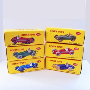 May include: A collection of vintage Dinky Toys racing car models in their original yellow boxes. Each box features a different car design, including Alfa Romeo, Maserati, and Ferrari, with the Dinky Toys logo and model number.