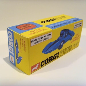 Könnte beinhalten: Eine gelbe Schachtel mit einem blauen und weißen Spielzeugauto auf der Vorderseite. Die Schachtel trägt die Aufschrift "Corgi Toys" und "Chevrolet Astro 1 Experimental Car".