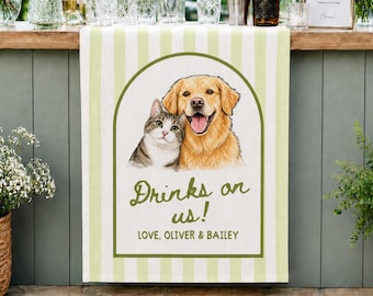May include: A light green and white striped table runner featuring a central illustration of a tabby cat and a golden retriever dog. The text reads Drinks on us! and LOVE, OLIVER & BAILEY. The runner is displayed on a bar with flowers and bottles.