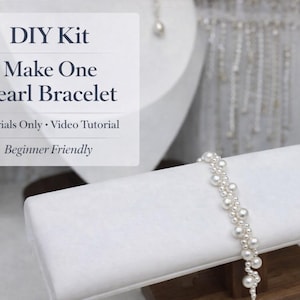 Könnte beinhalten: Ein DIY-Kit zur Herstellung eines Perlenarmbands. Das Bild zeigt ein fertiges Armband mit weißen Perlen, das auf einer weißen Schmuckform ausgestellt ist. Der Text auf dem Bild lautet "Make One Pearl Bracelet" und "Beginner Friendly".