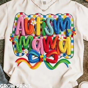May include: White t-shirt featuring the words "Autism Mama" in colorful, textured letters. The design includes a rainbow bow, flowers, and butterflies, all set against a checkered background. The brand name "GROW PRINT" is printed at the bottom.