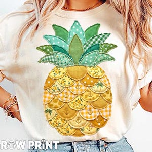 May include: Cream-colored t-shirt featuring a large, colorful pineapple design. The pineapple is made of various patterned fabrics in shades of green and yellow. The text "GROW PRINT" is at the bottom of the shirt.