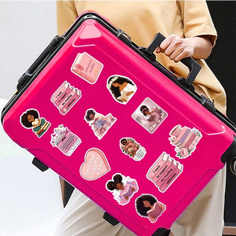 A person is holding a pink suitcase with various stickers on it.