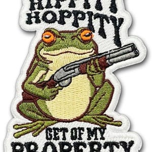 May include: Embroidered patch featuring a green frog with orange eyes holding a shotgun. The patch has the text "HIPPITY HOPPITY" above the frog and "GET OFF MY PROPERTY" below, all in black lettering on a white background.
