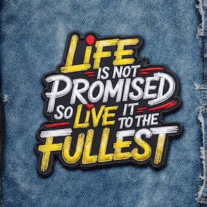 May include: Embroidered patch with the text "LIFE IS NOT PROMISED SO LIVE IT TO THE FULLEST" in yellow, white, and red on a black background. The patch is rectangular and has a black border. The patch is on a blue denim background.