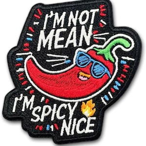 May include: Embroidered patch featuring a red chili pepper wearing blue sunglasses. The patch has the text "I'M NOT MEAN I'M SPICY NICE" in white lettering on a black background. The design includes a green stem and a small flame.