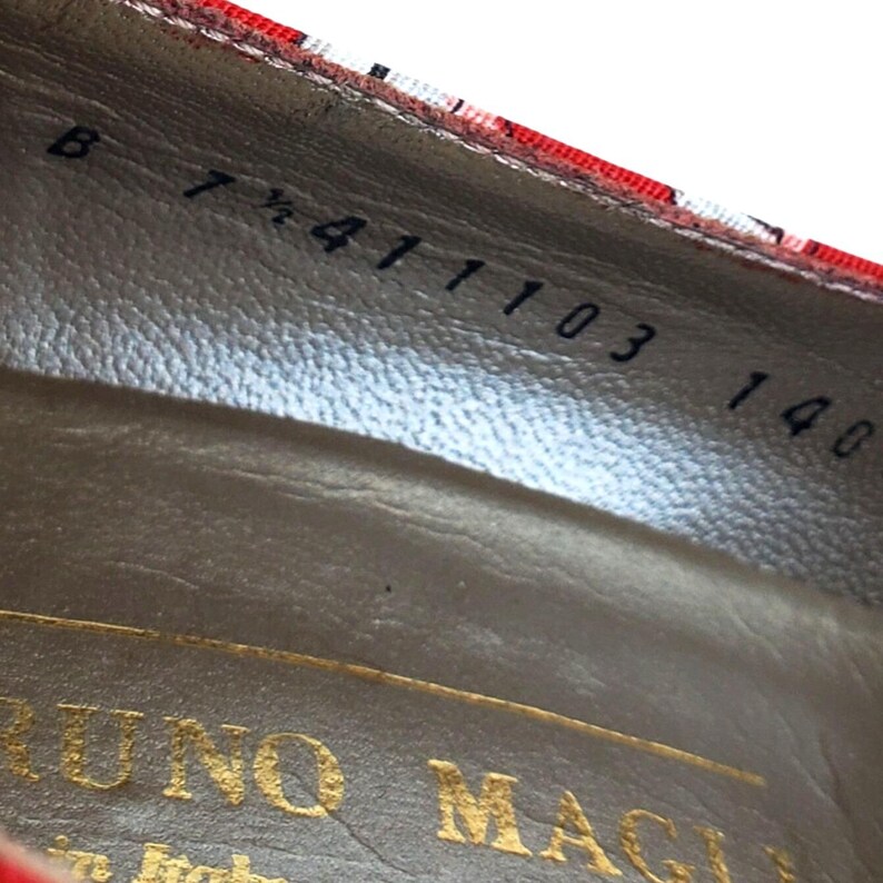 May include: Close-up of the interior of a red and white patterned shoe. The shoe's insole is a light brown color with gold lettering that reads "BRUNO MAGLI". The shoe size is 7 1/2.