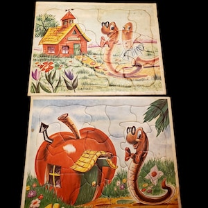 May include: Two vintage children's jigsaw puzzles. One puzzle features a red schoolhouse with the word "School" on it and two cartoon worms. The other puzzle shows a red apple house and a cartoon worm.