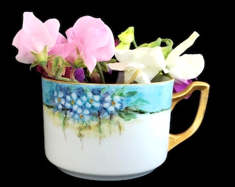 Taza de té antigua de porcelana pintada a mano con asa dorada y flores azules
