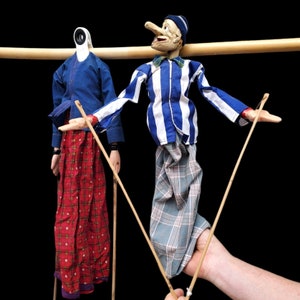 May include: Two puppets on sticks, one with a blue and white striped shirt and a blue hat, the other with a blue shirt and a red and black plaid skirt.