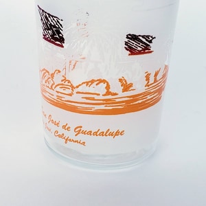 May include: A white glass with an orange and brown illustration of a scene from San José de Guadalupe, California. The text "San José de Guadalupe, California" is printed on the glass.
