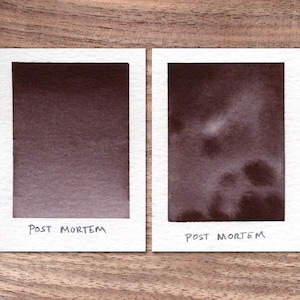 May include: Two ink swatches on white paper, both labeled "POST MORTEM". The swatch on the left is a solid dark brown color. The swatch on the right is a lighter brown with a mottled, cloudy appearance.