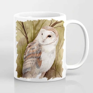 May include: White ceramic mug with a watercolor illustration of a barn owl with brown and white feathers. The owl is perched in a forest setting with brown branches and green leaves.