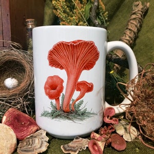 Puede incluir: Taza de cerámica blanca con una ilustración roja y blanca de tres setas. Las setas están representadas de forma realista con un fondo verde.