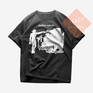May include: Dark gray t-shirt featuring a white graphic of a figure pointing towards a cloud-like shape, with the text "dean blunt • soulonfire" above. The word "gut" is also visible in the graphic. The shirt is from Stacy Apparel.