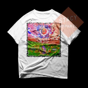 May include: White t-shirt featuring a colorful graphic design. The design includes an eye, a horse, and text that reads "BLOODAVE". The shirt also has a parental advisory label.